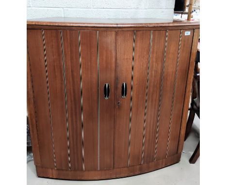 A retro/vintage walnut bowfront cocktail cabinet with 2 shelves, the base fitted for bottles, the doors fitted with cocktail 