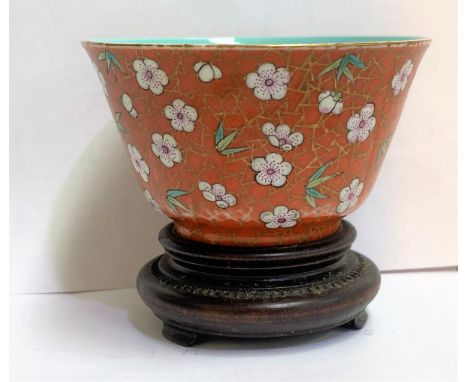 A Chinese porcelain tea bowl in red glaze with flowers on gilt lattice, seal mark to base, 4cm (some wear to gilt) with hardw