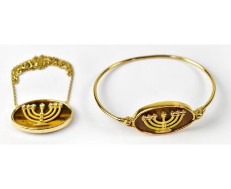 An 18ct yellow gold bangle with large oval tiger's-eye stone in gold frame, set with gold menorah in relief and seven small d