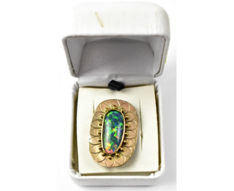 A modern 9ct gold and opal brooch, the elongated oval opal with dominant green, blue and red fire pigments, bezel set with an