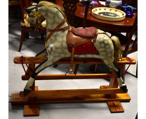 A dappled grey rocking horse mounted on a stain pine plinth and fitted with tan leather saddle and reins. with a corduroy pad