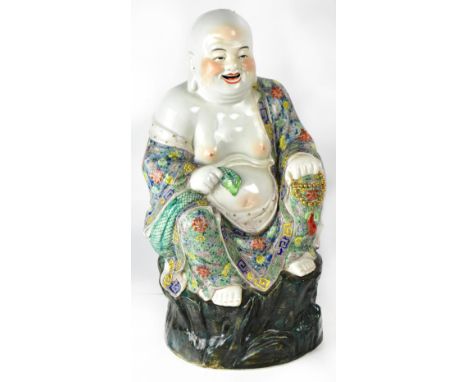 A Chinese Republic period ceramic figure of a seated Budai, with vibrant multicoloured robe decorated with flora in the Famil