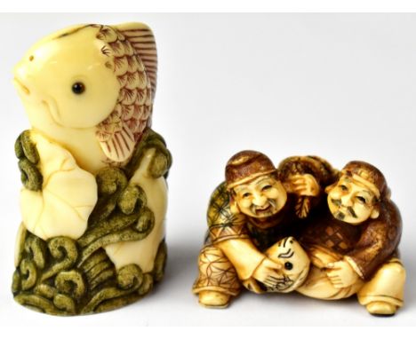 Two Japanese netsuke on in the form of a carp swimming through lily pads and a pair of fishermen holding a sack and fish betw