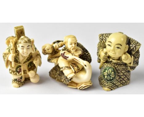 Three Japanese netsuke comprising a man and child riding a stork, a man carrying a mask and other items on his back in one ha