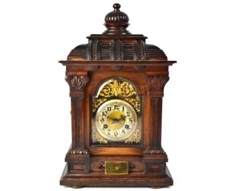 A large early 20th century eight-day mantel clock, the silvered chapter ring set with Arabic numerals within applied scrollin