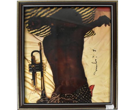 MILES DAVIS; a photograph of the star lying on a bed with trumpet by his side, bearing his signature and with further signatu