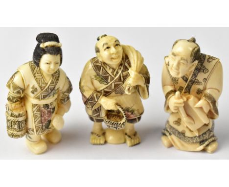 Three Japanese netsuke comprising a calligrapher holding a brush and scroll, a man holding a sack across his shoulder in one 