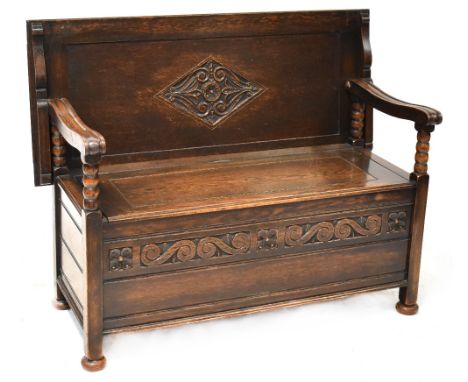 A 19th century and later oak monk's bench with bobbin turned supports, hinged box seat with carved foliate decoration to the 