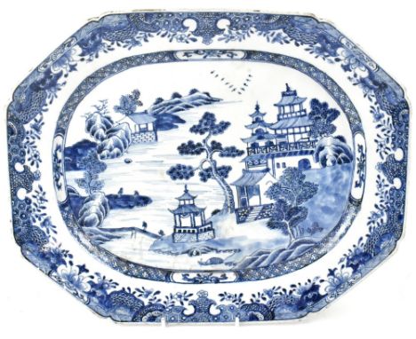 A Chinese Export blue and white meat plate painted with pagodas and a house within a lakeside scene, the borders with scroll 