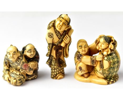 Three Japanese carved netsuke comprising a scholar holding a scroll, a crouching man holding up a sack with a child poking ou