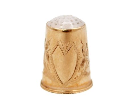A 14k rose gold thimble with white hardstone set top. With foliate scroll bright cut decoration and vacant cartouche, stamped