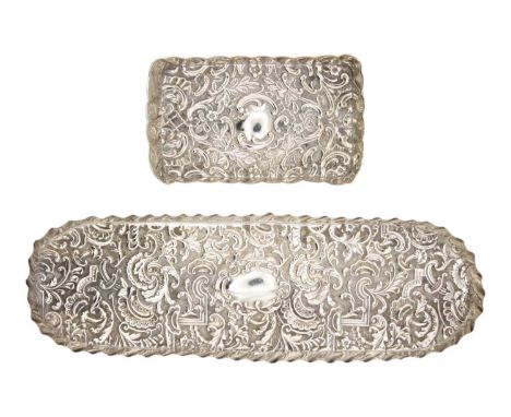 Two Victorian silver embossed dressing table pin trays. One is oblong and decorated with foliate scrolls and strapwork, maker