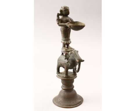 AN 18TH CENTURY INDIAN BRASS OIL LAMP, in the form of dipa lukshmi on an elephant, 24cm high x 8.5cm wide.