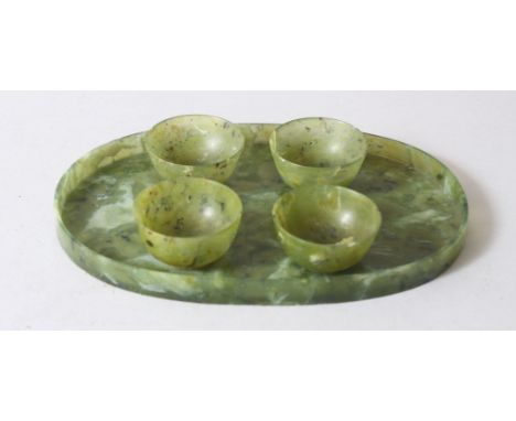 A CHINESE MOTTLED GREEN JADE OVAL TRAY AND FOUR TEA BOWLS, tray 16cm wide.
