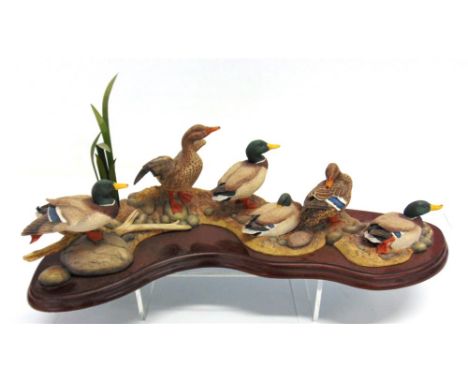 A BORDER FINE ARTS GROUP OF SIX MALLARD DUCKS on a pebble bank amongst rushes and driftwood, by R Roberts and dated 2002, No: