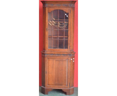 An oak floor standing corner cupboard, outswept cornice, astragal glazed door to top, fielded panel door to base, ogee feet