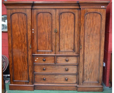 A Victorian mahogany inverted breakfront compactum wardrobe, ogee cornice, arched panel doors enclosing slides over two short