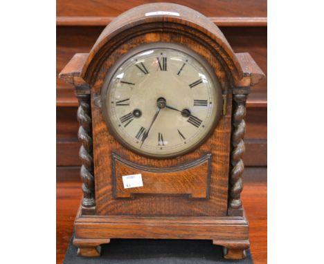 An oak cased mantel clock, barley twist columns