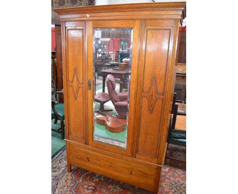 An Edwardian light oak wardrobe, ogee cornice, central mirrored door, deep drawer to base, brass pendant handles. 197cm high 