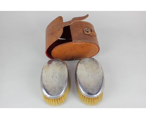 A pair of George V silver mounted gentleman's brushes, maker William Neale & Son Ltd, Birmingham 1923, monogrammed, in leathe