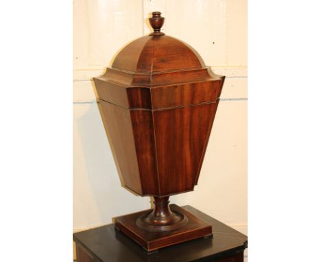 A George III mahogany urn shaped box with domed lid and finial (detached), tapered form with concave corners, on pedestal sup