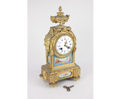 A French gilt metal and porcelain mantel clock, with vase surmount and cover, white enamel dial in domed case, with side mask