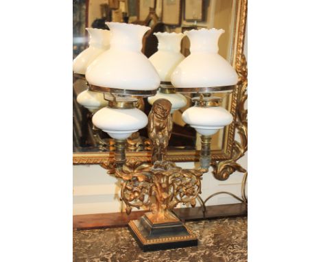 A gilt metal two-branch table lamp modelled in the form of an oak tree with central owl figure and prey, two opaque glass sha