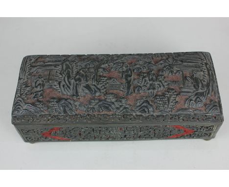 A Chinese cinnabar lacquer rectangular box, the hinged lid decorated in relief, with figures and pavilions in woodland, blue 