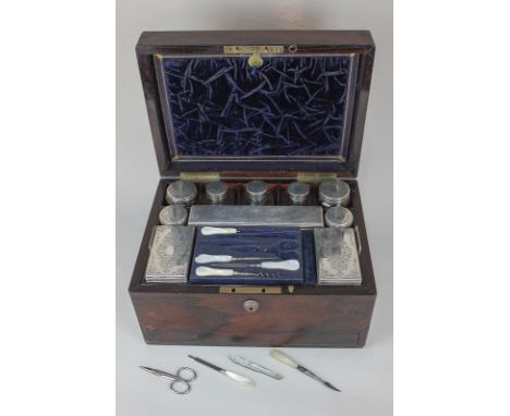 A Victorian rosewood dressing table box containing ten matched silver topped glass boxes and jars, some marked James Vickery,