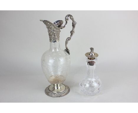 A Victorian silver mounted glass ewer with scroll handle and circular floral embossed base, maker William Comyns, London 1893