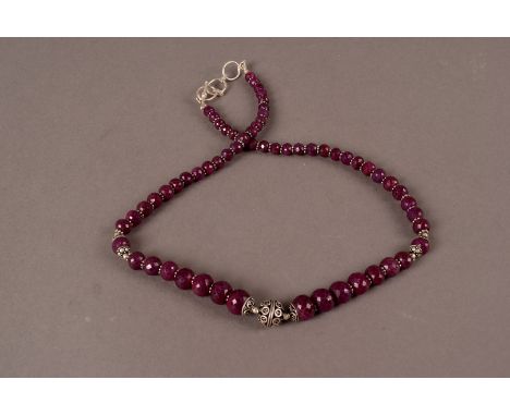 A faceted ruby necklace,  the graduated beads set with silver ring spacers 