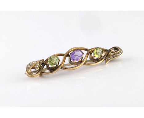 An early 20th century yellow metal amethyst, peridot and seed pearl bar brooch in the suffragette colours the scrolling openw
