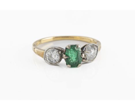 An 18ct yellow gold emerald and diamond three stone ring the central oval mixed cut emerald flanked by two old cut diamonds a