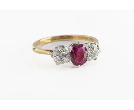 An 18ct yellow gold ruby and diamond three stone ring the central oval cut ruby, flanked by two old cut diamonds approx 1ct t