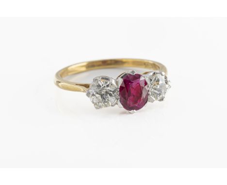 An 18ct yellow gold ruby and diamond three stone ring the central oval cut ruby, flanked by two old cut diamonds approx 1ct t