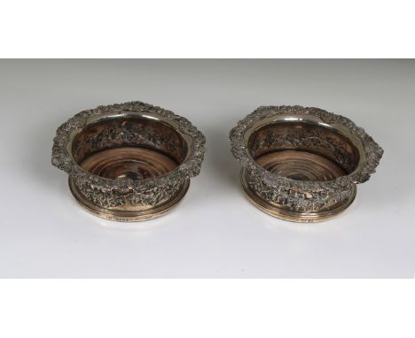 A matched pair of late Georgian silver wine coasters probably John Hawkins, London,1822 &amp; 1828, scrolling grape vine deco