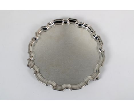 A 20th century silver salver Wakely &amp; Wheeler, London, 1973, with scalloped pie crust edge, on three periwinkle shaped fe