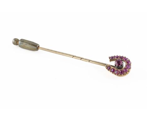 An Edwardian yellow metal and ruby horseshoe stick pin centered with a round-cut ruby, approx 4mm, within a horseshoe of elev