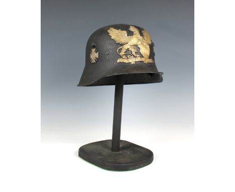 A trench art German helmet on stand mounted with helmet plate and badges.