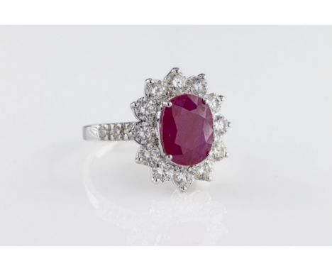 An 18ct white gold ruby and diamond cluster ring, the oval mixed-cut ruby 3.34 carats, surrounded by round brilliant-cut diam