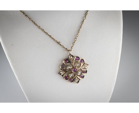 A yellow metal ruby and pearl pendant the shaped pierced frame set with round cut rubies and seed pearls, suspended from a ye