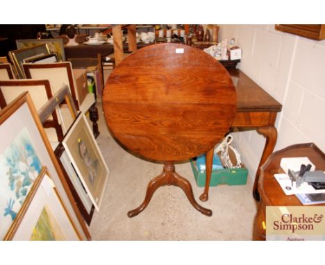 A 19th Century circular oak snap top occasional table raised on baluster column and tripod base 