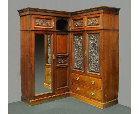 A large late Victorian corner wardrobe, fitted with a series of doors, drawers and cupboards and raised on a plinth base.  He