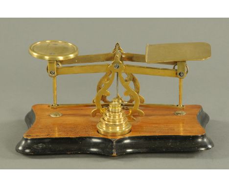 An Edwardian walnut set of postal scales, with weights, on shaped base.  Width 29 cm. 