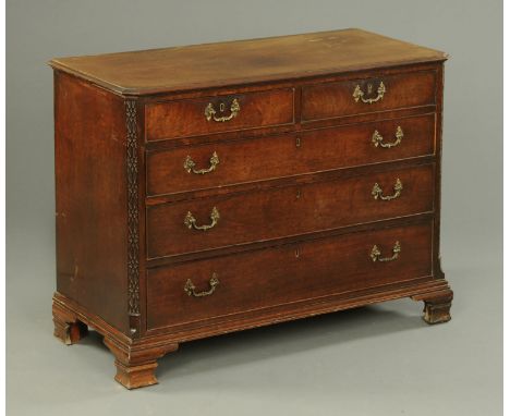 A George III mahogany chest of drawers, with moulded edge, canted angles with blind fretwork, two short and three long gradua