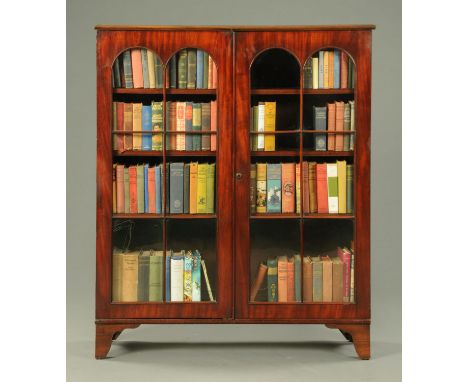 A mahogany bookcase, with moulded cornice above a pair of arched glazed doors enclosing adjustable shelves and raised on brac