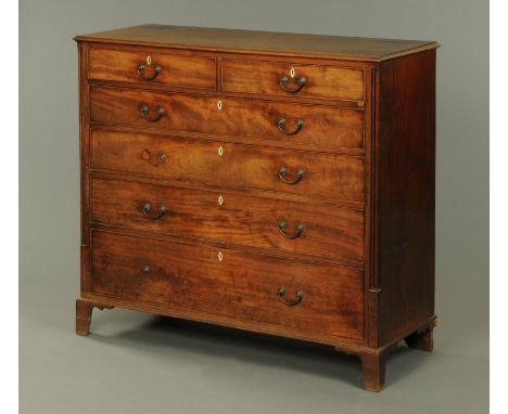An early 19th century mahogany chest of drawers, two short and four long drawers with brass drop handles and flanked by clust