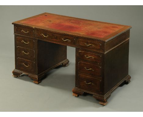 An oak pedestal desk, with tooled leather writing surface, frieze and pedestal drawers and raised on bracket feet. Width 138 