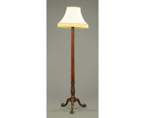 An early 20th century mahogany lamp standard, with reeded and carved column with three downswept legs terminating in claw and