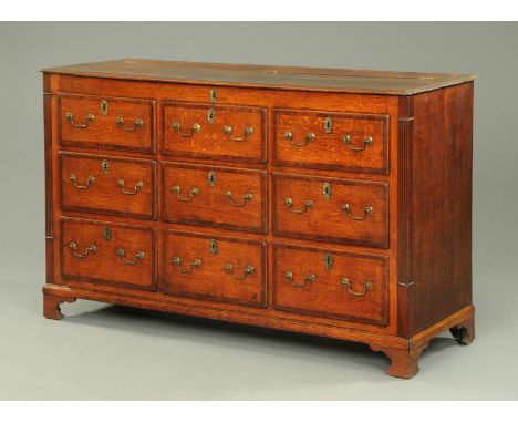 A George III oak mule chest, with moulded edge to the hinged top, the front modelled as a series of false drawers, with three